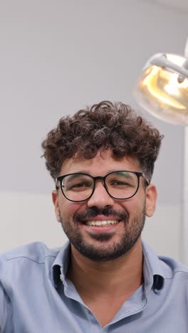 young man with curly hair and stylish glasses in a shirt at bright modern dental office young man with curly hair and stylish glasses in a shirt at bright modern dental office
