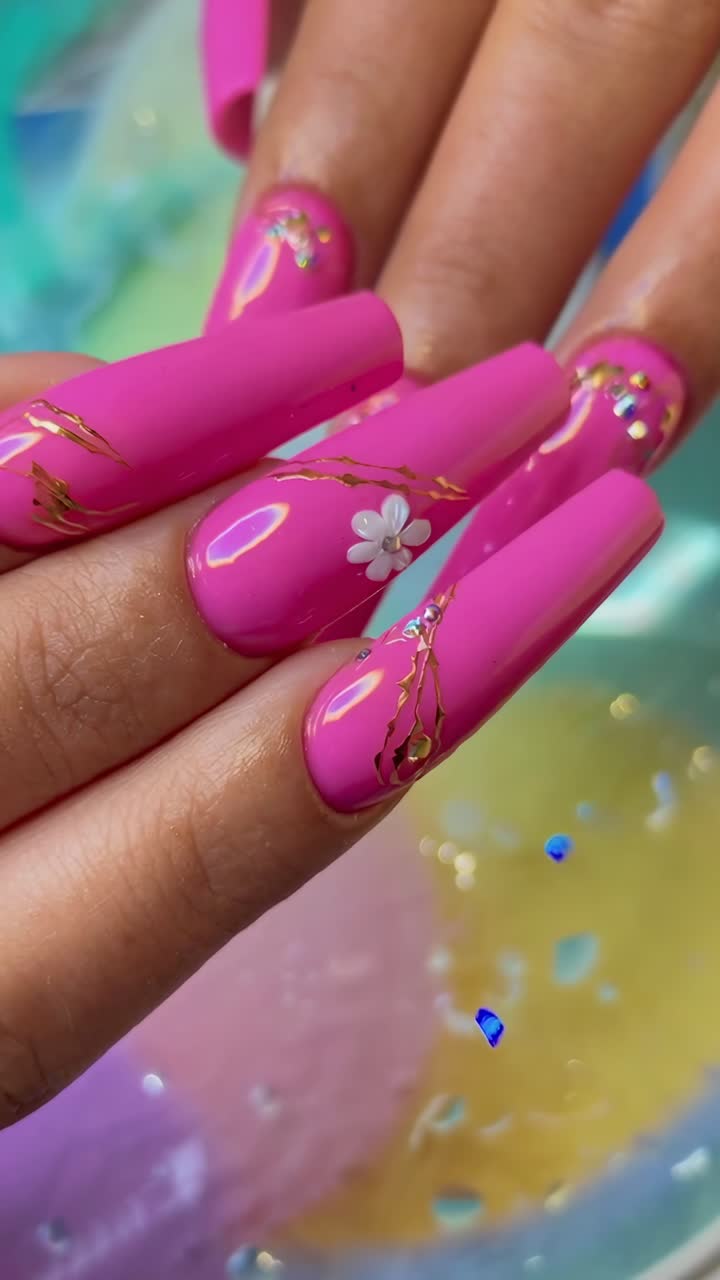 Close-up video of vibrant pink nails with floral designs, shot from a top-down angle