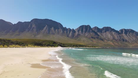 white sand beach with clear blue ocean with beautiful mountains in the background, kogel, south africa