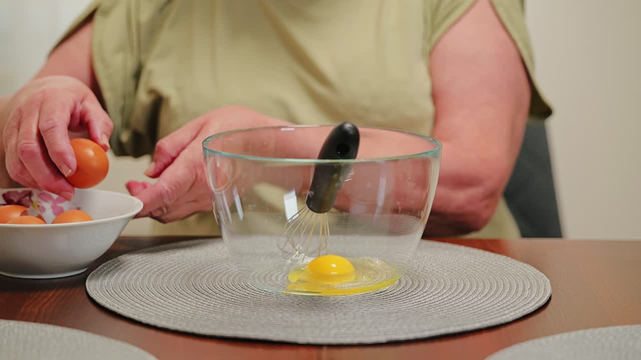 Latvian grandma cracks fresh farm eggs into glass bowl, front angle kitchen shot
