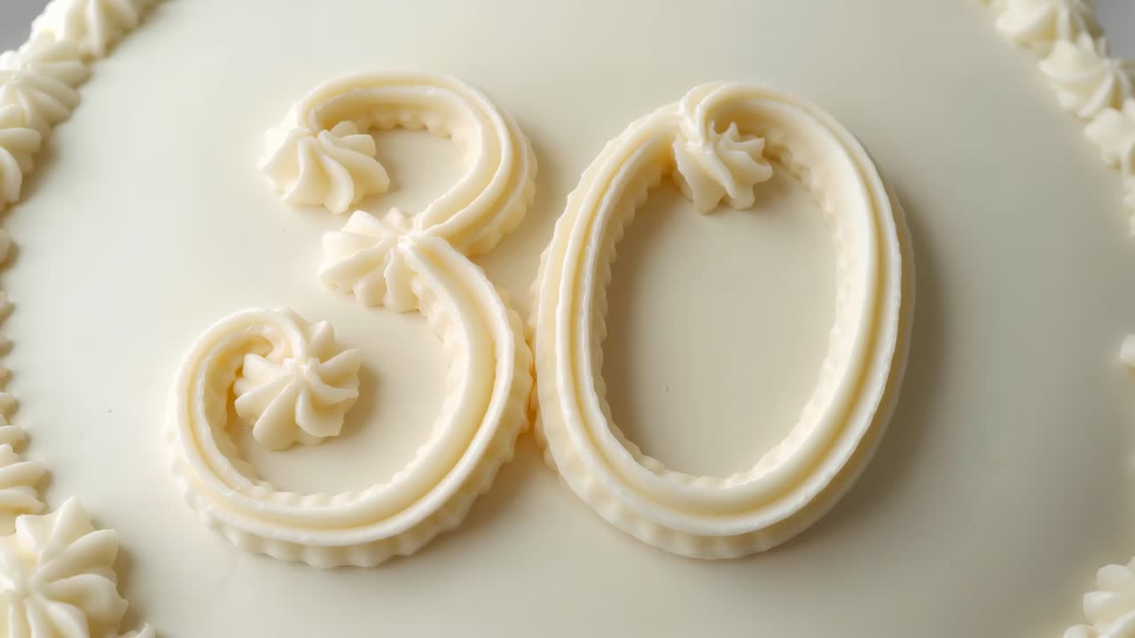 Shifting camera revealing round cake top featuring piped '30' frosting on cake board for display