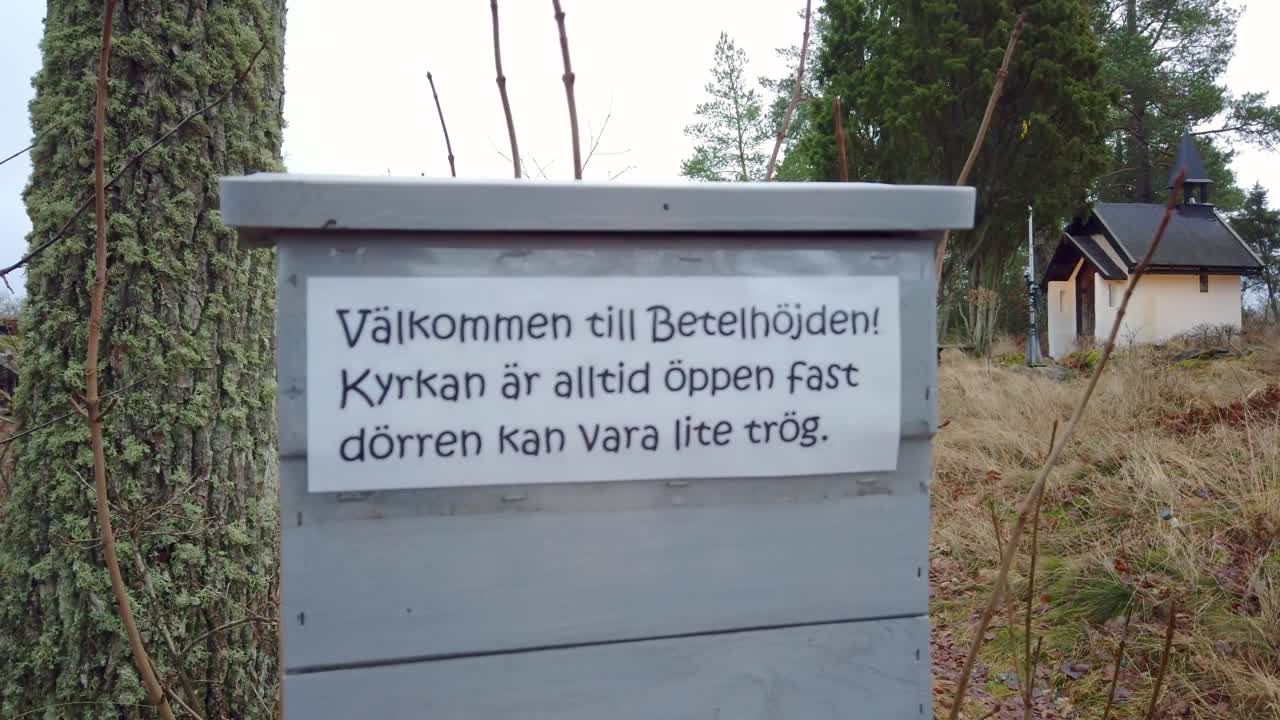 Welcome sign to the smallest church in Sweden. Handheld, pan right