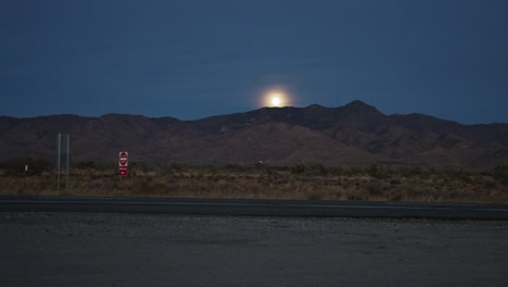 Video-De-Lapso-De-Tiempo-De-La-Luna-Saliendo-Sobre-Una-Cordillera-Con-Vehículos-Pasando-Por-Nevada