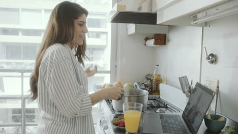 woman cooking food and video calling in the kitchen