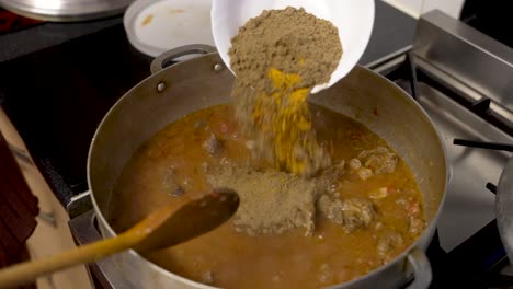 una escena culinaria se desarrolla mientras las especias y el polvo de curry se salpican en un delicioso estofado de carne, capturando la esencia de la preparación de la comida y el disfrute de la cena