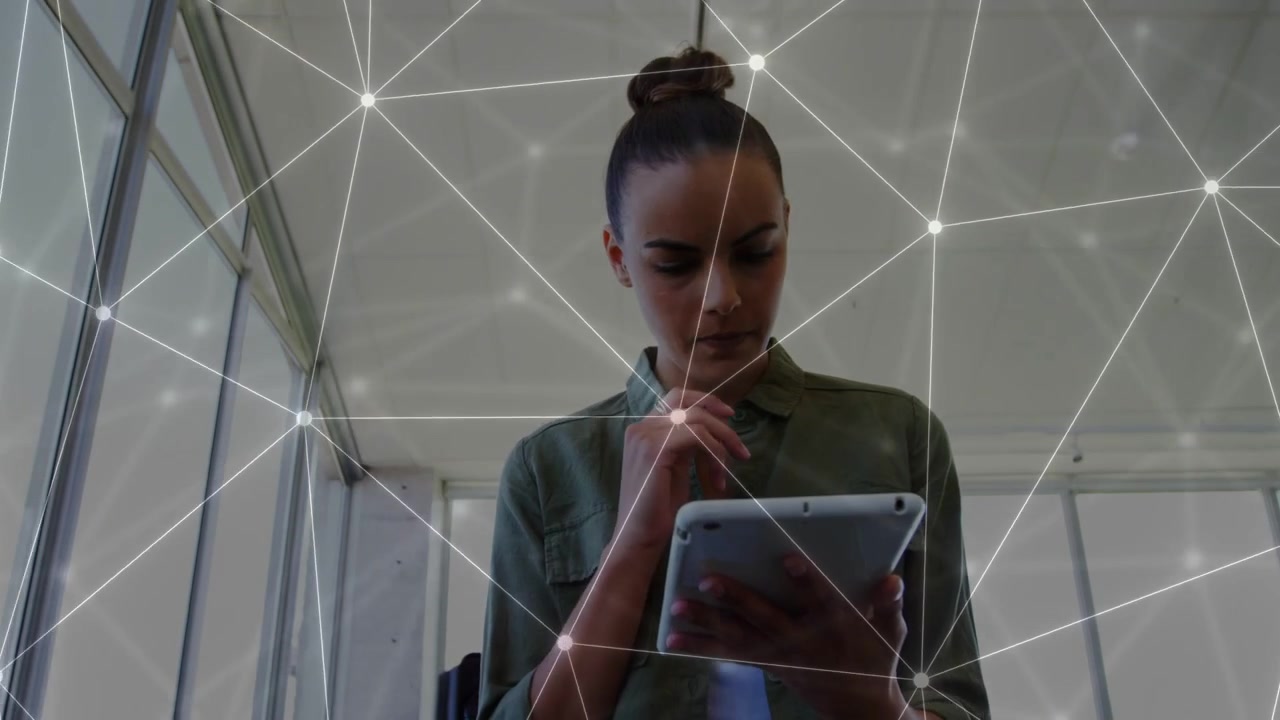 Donna in piedi in ufficio che usa un tablet e naviga un'interfaccia di rete sullo schermo per analisi tecnologica