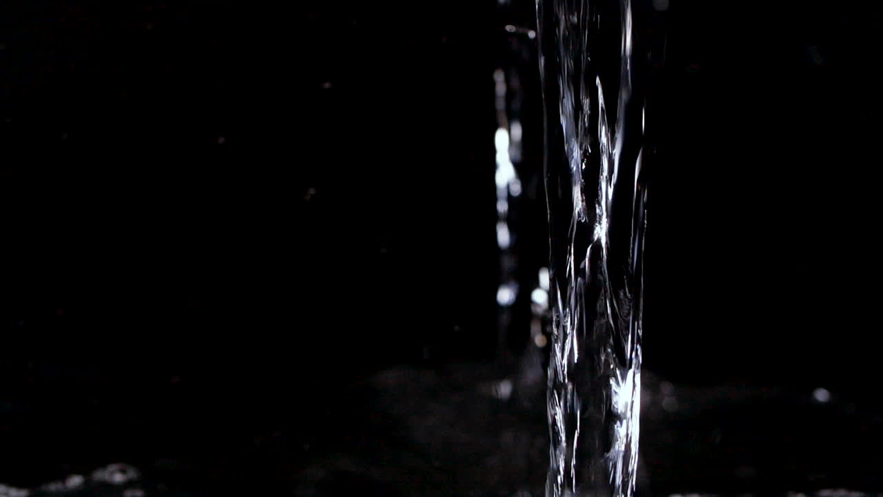 Acqua fresca e rinfrescante che si versa su sfondo nero al rallentatore, Idratazione