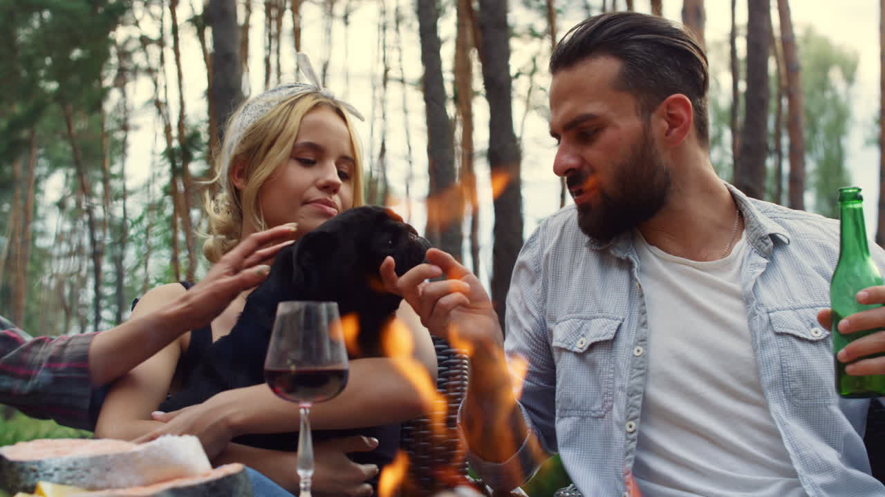 뒷마당에서 손에 개를 들고 있는 매력적인 여자. 밖에서 개를  ⁇ 는 남자