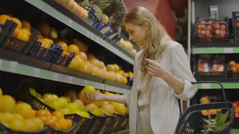 mujer escogiendo limones a mano en la tienda de comestibles recoge limones en el pasillo de frutas y verduras en un supermercado