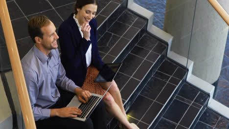 Business-colleagues-working-on-laptop-and-digital-tablet-in-stairs-4k