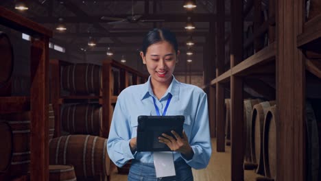 asian female professional worker standing with her tablet in cellar of winery, work continuously with her tablet
