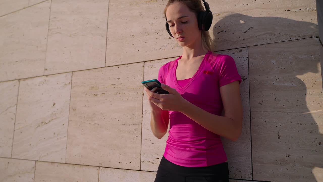 mujer con auriculares usando teléfono inteligente afuera