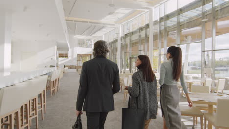 three businesspeople walk through a modern hotel lobby or restaurant