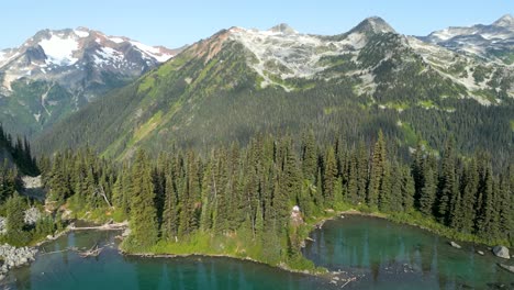 Flying-above-the-lake-parallel-to-the-mountain-edge-with-snowy-peaks-in-the-background