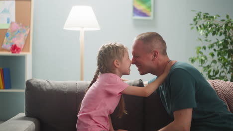 joyful father and little daughter touch noses in living room