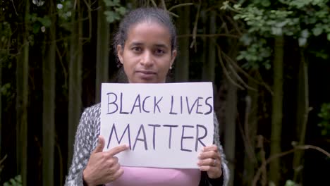 young black woman holds "black lives matters" poster and points on it