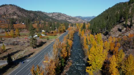 vista aérea descendente de autos que pasan por un pequeño pueblo rural en el bosque junto al río en washington, estados unidos