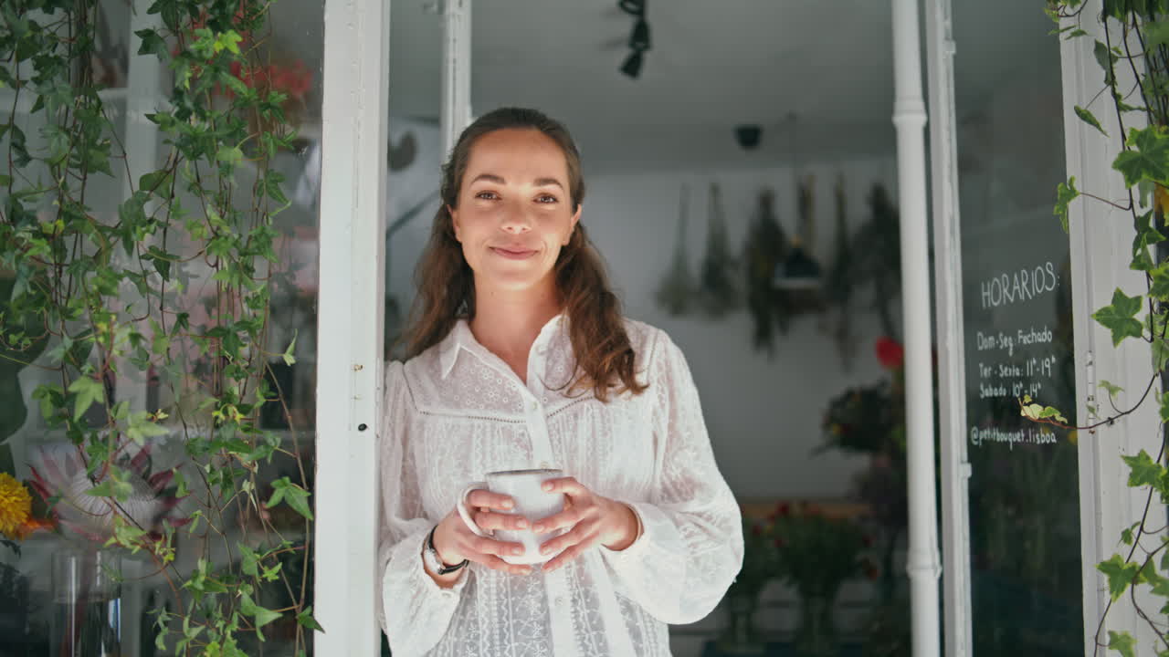 웃는 사업가 여성은 꽃 가게에서 커피를 마시고 행복한 꽃가게를 즐기며 하루를 시작합니다.