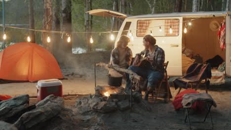 Pareja-Tocando-La-Guitarra-Y-Cantando-En-El-Campamento-Por-La-Noche