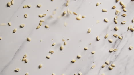 disparo aéreo de cacahuetes cayendo sobre la superficie de mármol disparado en cámara lenta