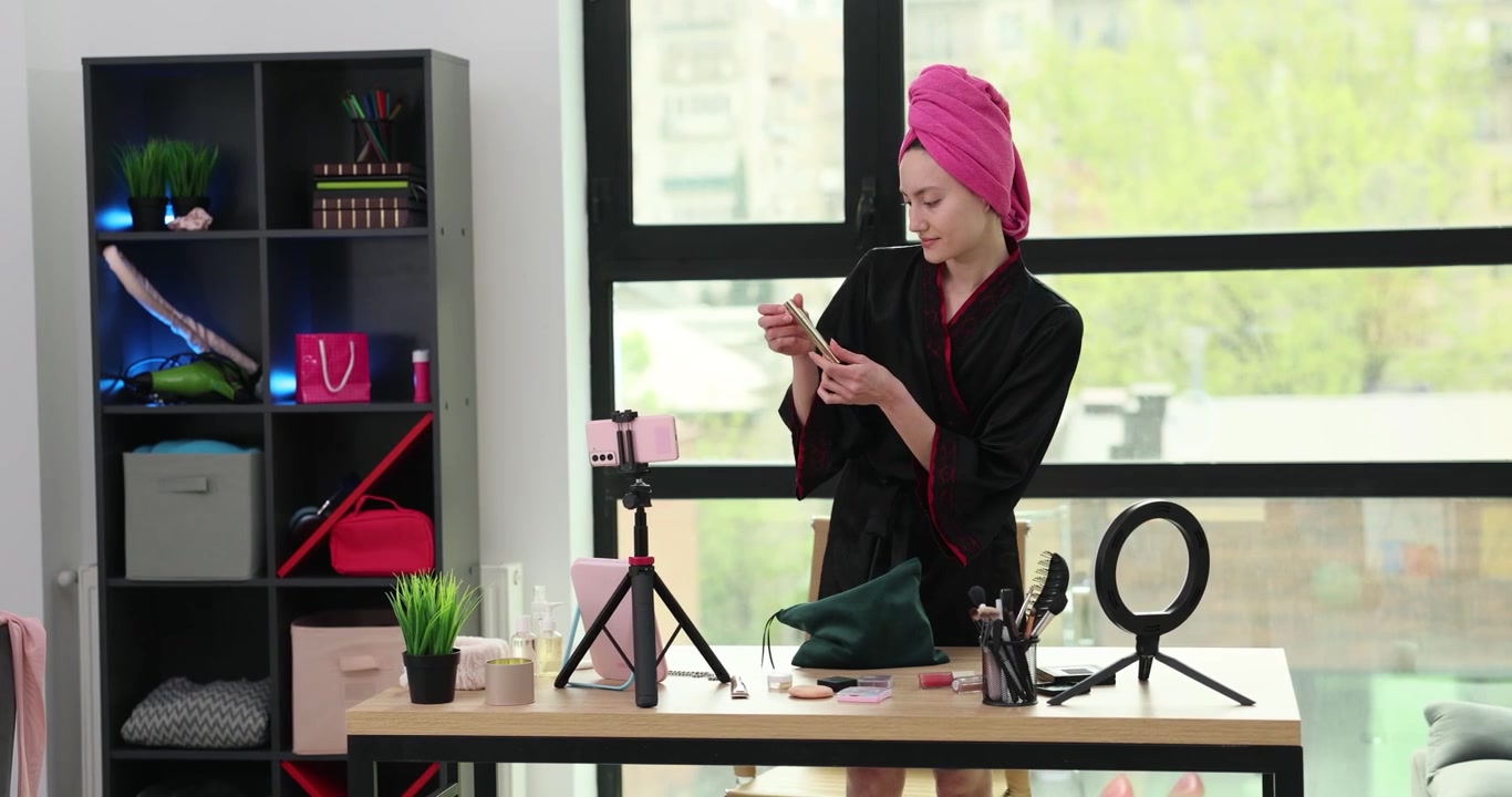 Woman beauty blogger with towel on head unpacks cosmetic bag