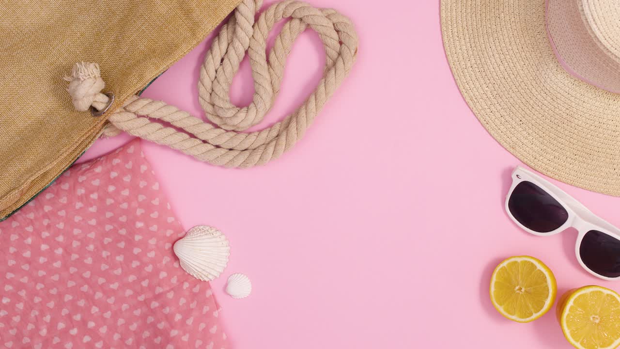 Bolso de playa de verano, sombrero y accesorios se mueven sobre un fondo rosa pastel con espacio para texto. Animación stop motion en vista cenital