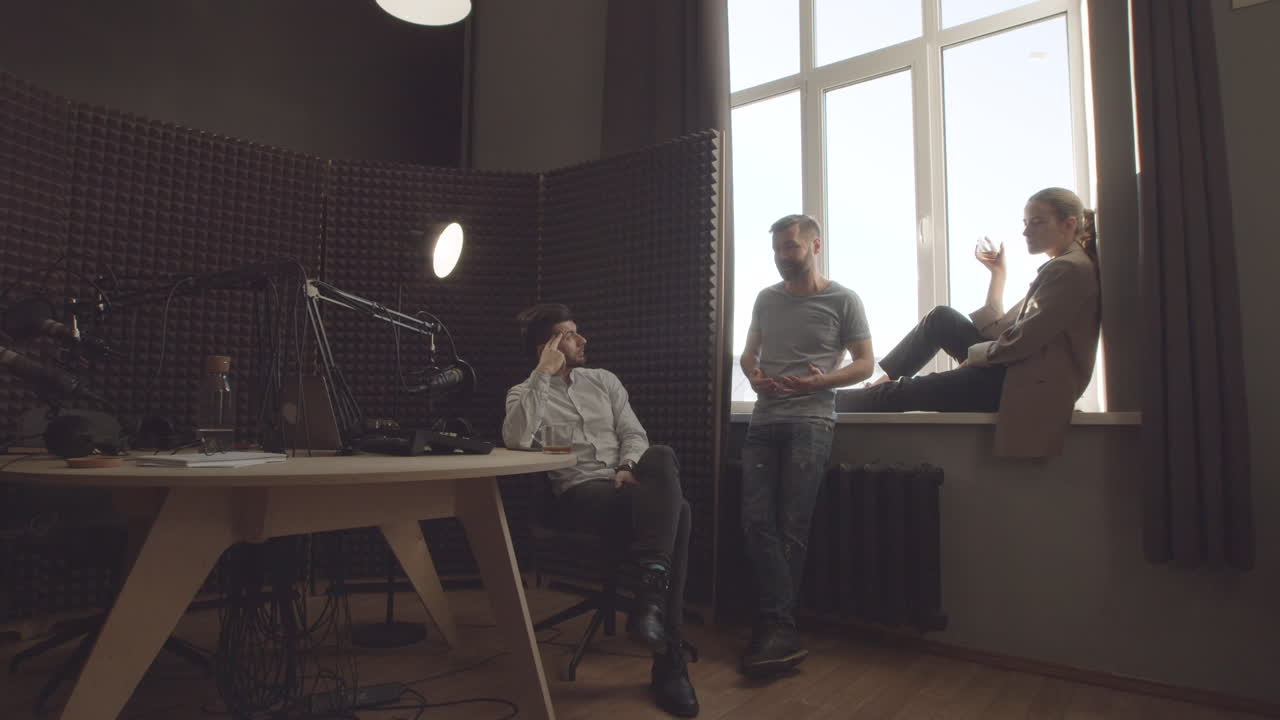 три стильных и инициативных молодых специалиста, непринужденно беседующих в радиостудии перед записью или после нее