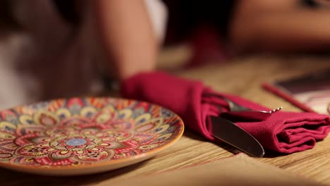 vibrant plate with intricate design on a wooden table in a bangkok restaurant, set with red napkins and cutlery