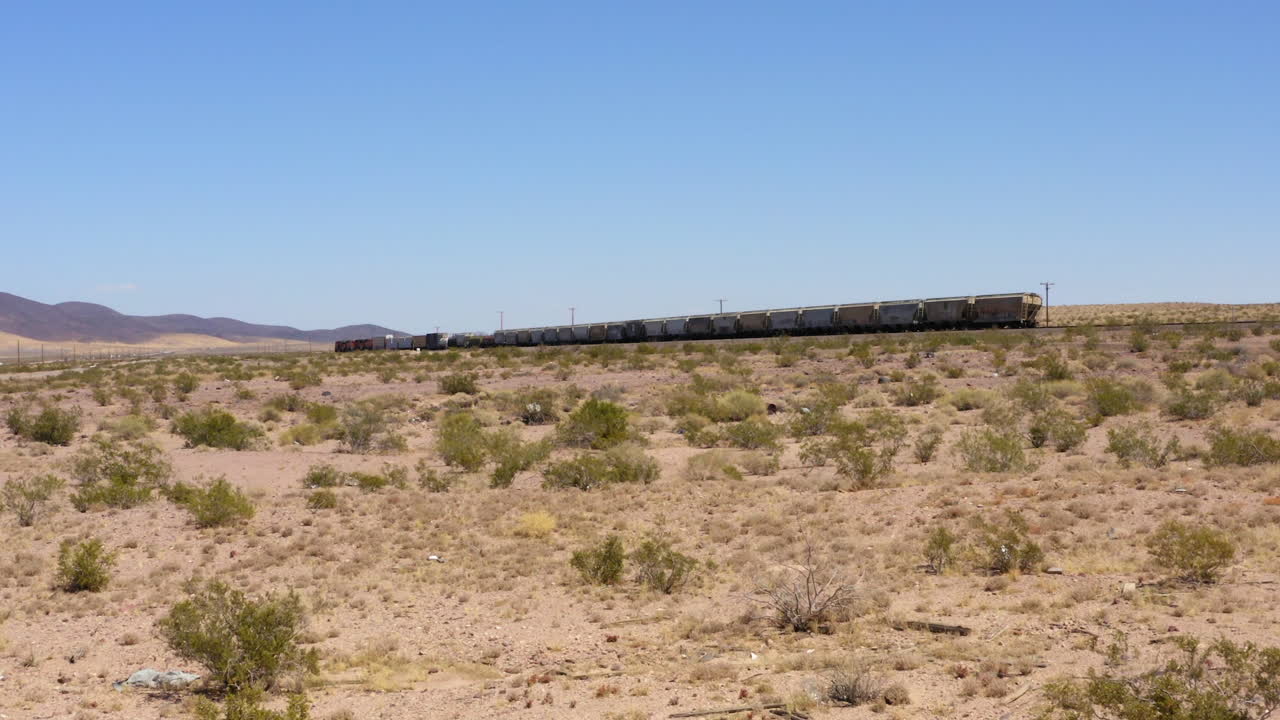 tren de carga corto que transporta mercancías a toda velocidad por vías de tren rectas en el desierto