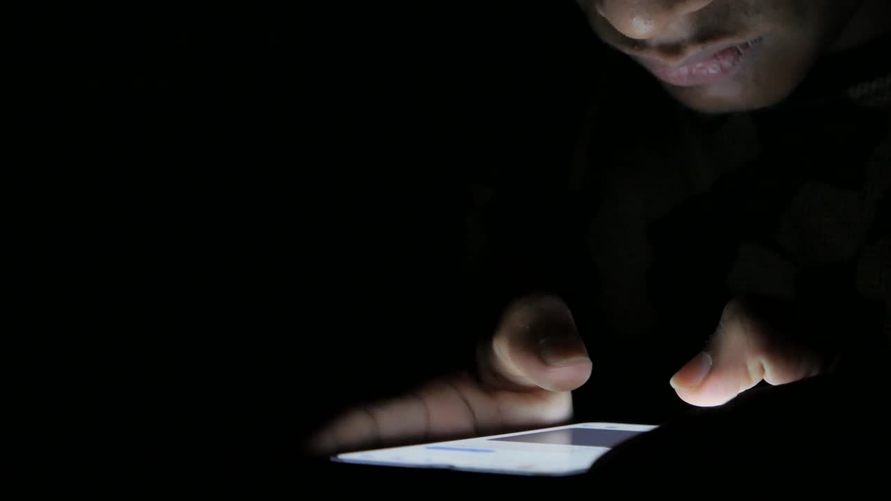 Uomo che usa lo smartphone al buio
