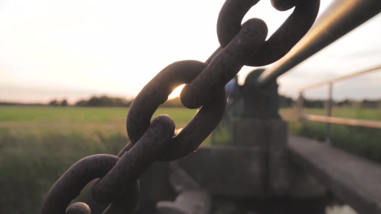 해가 지는 동안 얼룩진 체인 링크 다리