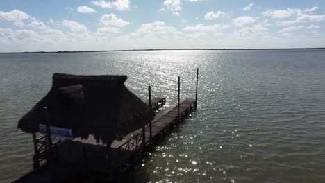 forward-flight-over-wooden-dock-at-lake-blue-sky-and-bird-following-chelem-yucatan-mexico