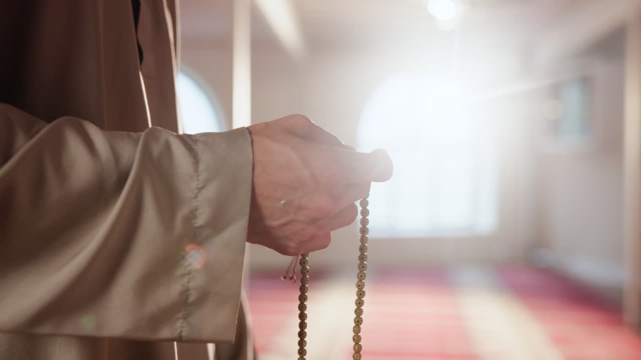 Muslim man praying with prayer beads in a mosque