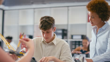 female teacher with male high school student using digital tablet in stem class