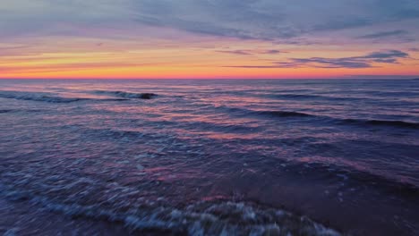 low flight over the shore of a snowy empty beach under epic and scenic colorful sunset