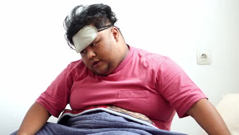 overweight man awakening and stretching his body while still wearing his eye mask