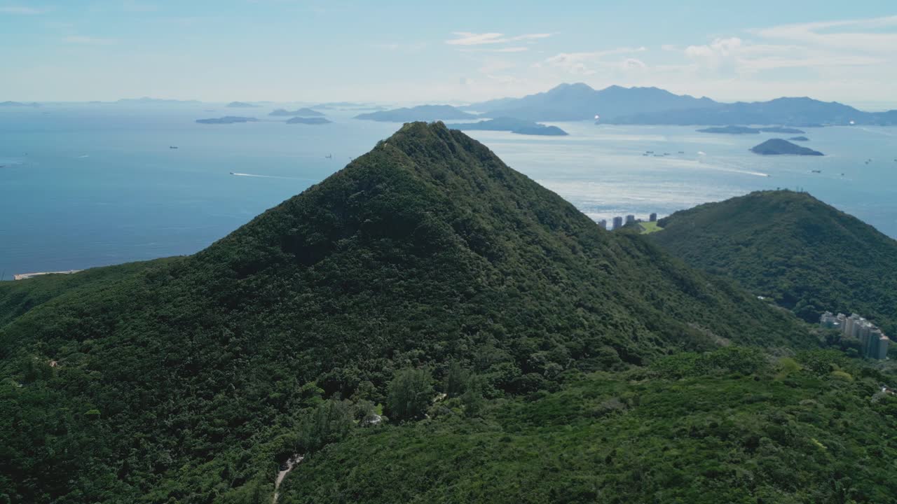 Aerial drone footage capturing Hong Kong’s lush mountains overlooking the ocean, showcasing scenic coastal landscapes, natural greenery, and panoramic vistas