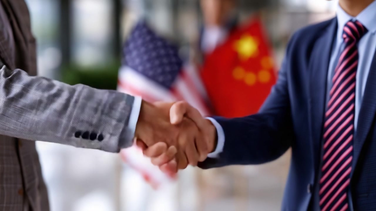 Poignée de main entre professionnels des affaires symbolisant la coopération et la collaboration, au milieu de drapeaux représentant deux nations, dans un cadre professionnel.