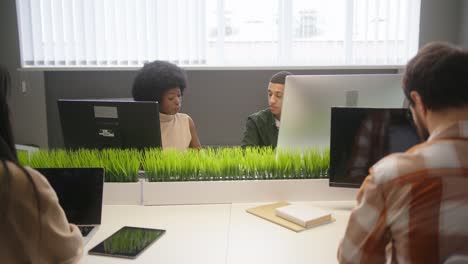 multinational people sit at desks working on computers