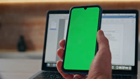 man hand touching green screen mobile answering videocall at workplace closeup