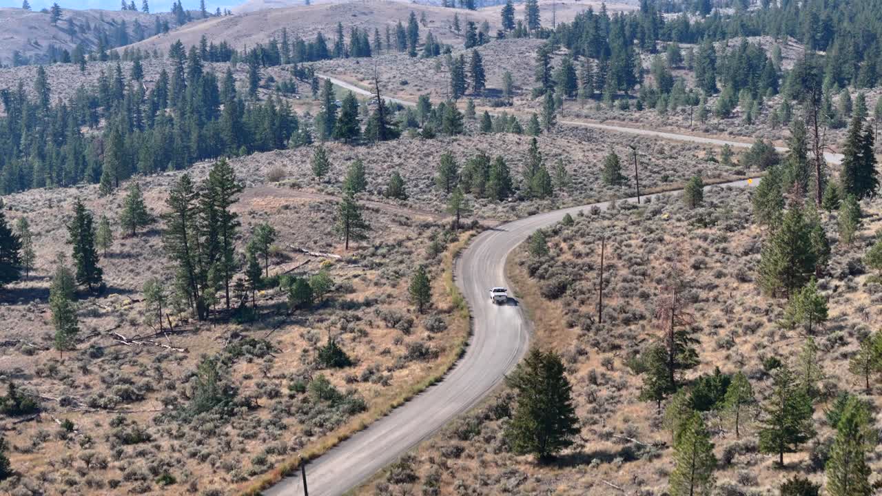 desde arriba: una camioneta viaja por una polvorienta carretera del desierto en un paisaje boscoso