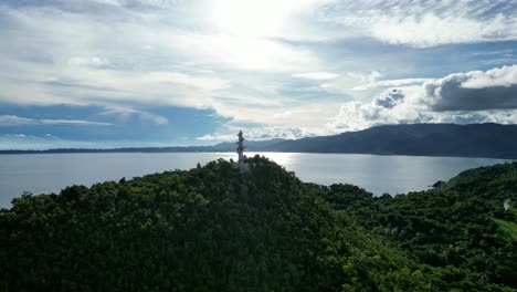 approaching drone shot of high-contrast view of bote lighthouse atop rainforest-covered hills in the island of catanduanes