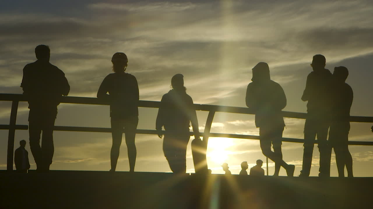 Venice Beach Skate Park at Sunset. Skaters and spectators silhouetted by the sun. Slow Motion