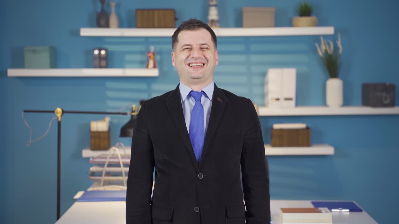 비즈니스맨은 사무실에서 카메라를 보고 자신이 만족하고 행복하다는 것을 표현합니다.