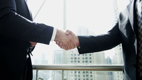 handshake between businessmen financial tower downtown city building