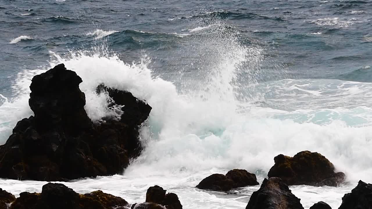 Close-up of waves crashing over black lava rock along the road to Hana, Maui, Hawaii