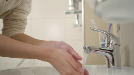 woman washing hands and face in bathroom