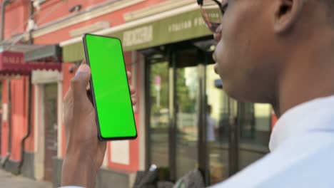 african man looking at smartphone with green chroma screen