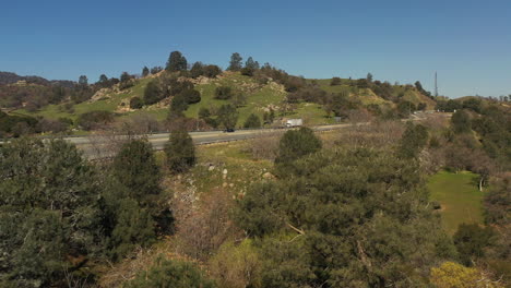 a highway through the heart of the tehachapi mountains in spring with green grass - aerial view