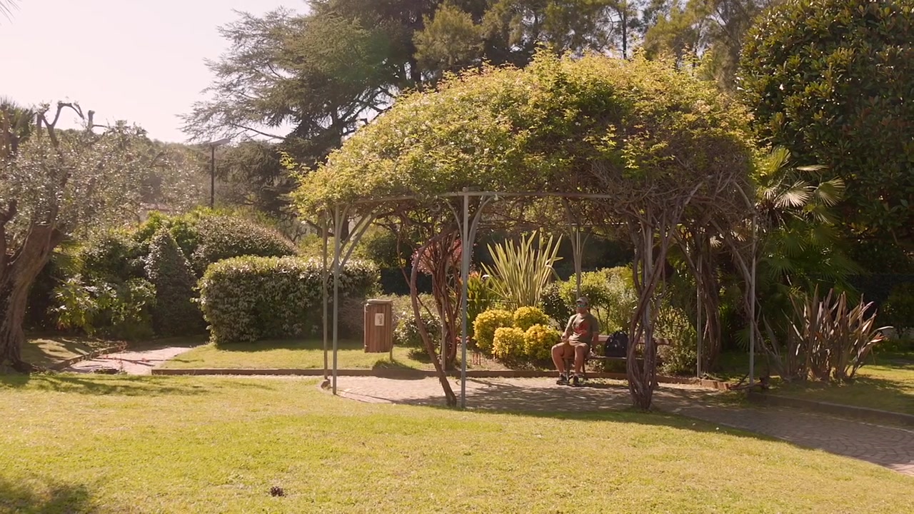 Vista amplia de un apuesto joven disfrutando de su tiempo libre en un jardín público en un espacio exterior soleado, Saint Jean Cap Ferrat, Francia.